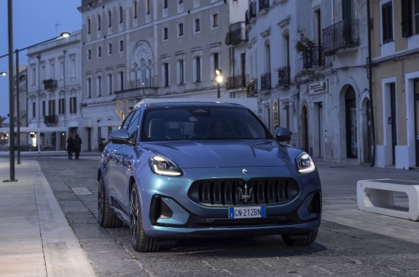 A 2025 Maserati Grecale Folgore drives on a street in the evening.